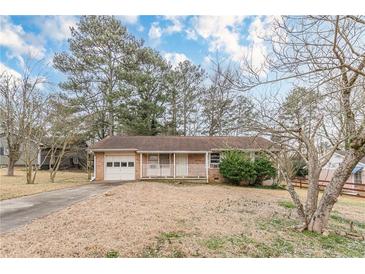 Charming brick home with a cozy front porch and attached garage, nestled in a serene, wooded setting at 301 Lady Agatha Ct, Jonesboro, GA 30236