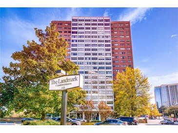 The Landmark Condominiums is a high-rise with a sign, trees, and a few cars parked in front of the building at 215 Piedmont Ne Ave # 204, Atlanta, GA 30308