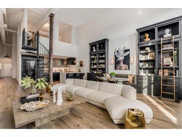 Spacious living room featuring a large sofa, spiral staircase, open-plan kitchen, and black shelving units at 170 Boulevard Se # 412E, Atlanta, GA 30312