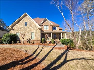 Charming two-story home with a covered porch, stone facade, manicured lawn, and mature trees at 1526 Rocky River Dr, Lawrenceville, GA 30045