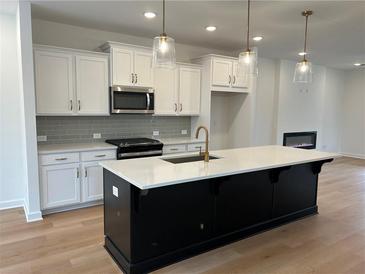 Bright kitchen features an island, stainless steel appliances, and a cozy fireplace in the background at 1932 Appian Aly, Kennesaw, GA 30144