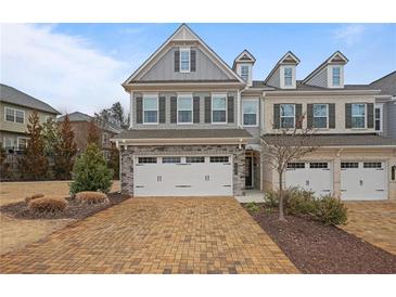 Charming townhome with a brick and gray facade, complemented by a two-car garage and patterned brick driveway at 100 Duval Dr, Alpharetta, GA 30009