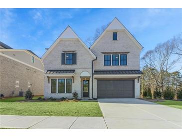 Elegant two-story home featuring a light brick facade, a two-car garage, and a well-manicured lawn at 3927 Enclave Way, Tucker, GA 30084