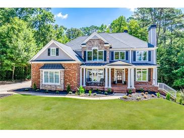 Stunning two-story home featuring a stone and brick facade with a manicured front lawn at 6690 Bridge Brook Ovlk, Cumming, GA 30028