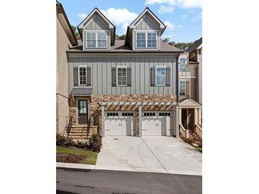 Beautiful townhome featuring a two-car garage, stone accents, vertical siding, and multiple windows at 302 Trecastle Ln # 27, Canton, GA 30114