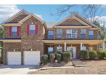 Charming brick home with a covered front porch, two-car garage, red shutters, and manicured landscaping at 248 Allegrini Dr, Atlanta, GA 30349