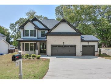 Beautiful two-story home featuring brick and white siding, a three-car garage and a well-manicured lawn at 58 Cherry St, Lawrenceville, GA 30046