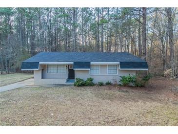 Ranch-style home features a brick facade, dark roof and door, trimmed bushes, and a lush, wooded landscape at 645 Plainville Sw Dr, Atlanta, GA 30331