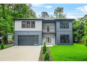 Two-story modern home with a two-tone exterior, balcony, large windows, and well-maintained landscaping at 921 Cone Rd, Forest Park, GA 30297