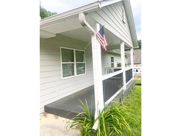 Inviting front porch featuring painted wood deck, siding and an American flag at 4567 Duncan Dr, Sugar Hill, GA 30518