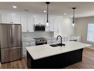 Modern kitchen with stainless steel appliances, island with white countertop, and stylish pendant lighting at 602 Birch River Ln, Lawrenceville, GA 30043