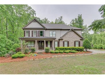 Charming two-story home featuring manicured landscaping, a covered porch, and a mix of brick and siding at 6225 Leeward Tide Ct, Cumming, GA 30041