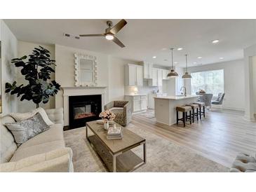 Open concept living room with fireplace, modern ceiling fan, and breakfast bar with pendant lighting at 2763 Sandy Rd, Conyers, GA 30013