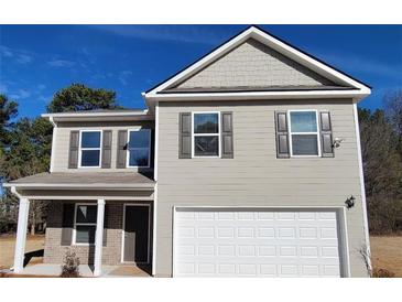 Two-story home featuring a white garage door, grey shutters, and a covered porch with brick accents at 140 Tye St, Stockbridge, GA 30281