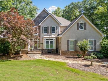 Charming two-story home with manicured lawn, stone accents and mature trees at 210 Lawn Market, Sharpsburg, GA 30277