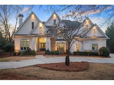 Stunning luxury home featuring a stone facade, arched windows, manicured landscaping, and a circular driveway at 3172 Ashford Dunwoody Ne Rd, Brookhaven, GA 30319