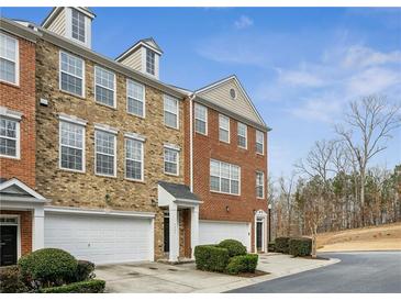 Brick townhouse with attached garages, trimmed bushes and front door entry, on a sunny day with blue skies at 4662 Creekside Villas Se Way, Smyrna, GA 30082