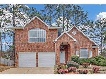 Charming brick two-story home with a two-car garage, arched entryway, and manicured landscaping at 560 Woodstone Rd, Lithonia, GA 30058