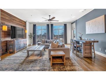 Open-concept living room with hardwood floors, modern furnishings, and large windows offering natural light and neighborhood views at 360 Chambers St # 301, Woodstock, GA 30188