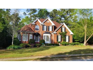 Charming two-story brick home with a manicured lawn and mature trees in a residential neighborhood at 1210 Thistle Gate Path, Lawrenceville, GA 30045