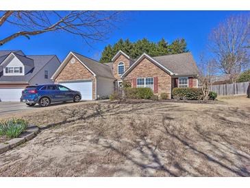 Charming single-story house featuring a stone facade, attached garage and blue car in the driveway at 1241 Skylar Ridge Cir, Buford, GA 30519