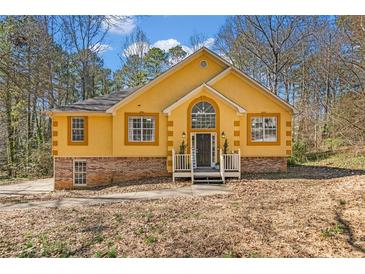 Charming mustard-yellow home features a brick foundation and a peaked roof with inviting front porch at 4804 Mceachern Way, Powder Springs, GA 30127