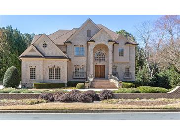 Stately brick home boasts manicured landscaping, arched entry, and multi-paned windows, providing curb appeal at 9070 Waits Ferry Xing, Johns Creek, GA 30097