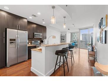 Bright kitchen featuring dark cabinets, stainless steel appliances, and granite countertops with bar seating at 1080 Peachtree Ne St # 2006, Atlanta, GA 30309