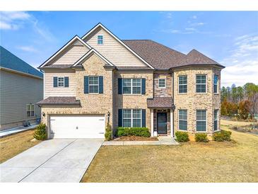 Stunning two-story brick home showcasing manicured lawn and attached two-car garage at 310 Nw Brightfield Dr, Loganville, GA 30052
