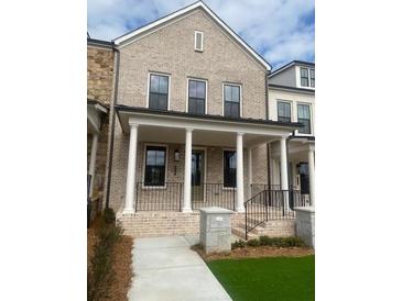 Charming two-story townhome boasts a light brick facade, covered porch, and well-manicured lawn at 110 Chiswick Cir # 40, Alpharetta, GA 30009