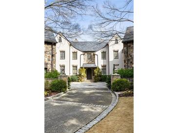 Elegant home exterior with stone and stucco, manicured landscaping, and a circular driveway at 675 W Paces Ferry Nw Rd, Atlanta, GA 30327