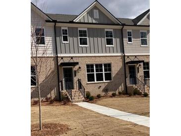 Charming two-story townhome with brick facade, gray siding, black door and small front yard at 1236 Ainsworth Aly # 37, Sugar Hill, GA 30518