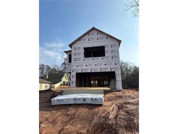 Exterior view of a framed two-story house under construction with visible building materials and open window spaces at 4862 Campbell Dr, Atlanta, GA 30349