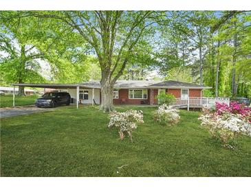 Charming single-story home with a lush green lawn, flowering bushes, and a convenient carport at 4033 Louise St, Powder Springs, GA 30127