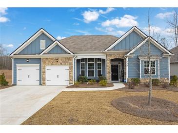 Charming home with blue siding, stone accents, a well manicured lawn, and a two-car garage at 7438 Jennadee Dr, Fairburn, GA 30213