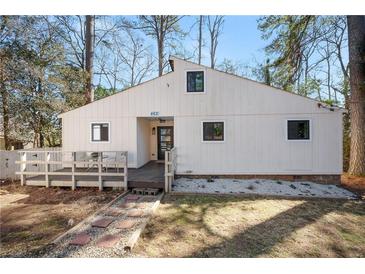 Charming home featuring a small deck, stone pathway, and white siding, surrounded by mature trees at 462 Lakeshore Dr, Stockbridge, GA 30281