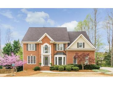 Charming brick home featuring a manicured lawn, blooming trees, and a welcoming front entrance at 445 Edenbrooke Way, Roswell, GA 30075