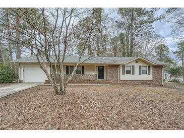 Charming ranch-style home featuring a brick facade and a well-maintained front yard with mature trees at 2102 Red Berry Sw Ln, Marietta, GA 30008