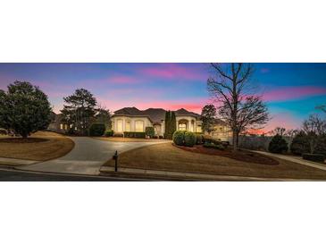 Stunning single-story home at dusk with manicured lawn, elegant architecture, and long drive at 1069 Eagles Brooke Dr, Locust Grove, GA 30248