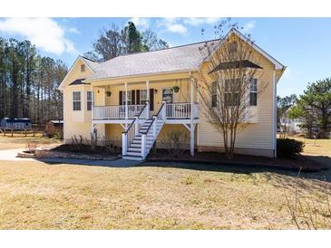 Charming yellow home features a welcoming front porch with white railing and a well-manicured lawn at 151 Berkshire Dr, Hiram, GA 30141