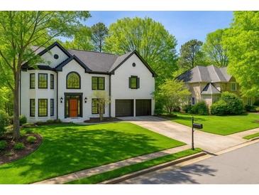Traditional two-story home with black shutters, symmetrical windows, gabled roof, and mature landscaping at 559 Fairway Dr, Woodstock, GA 30189