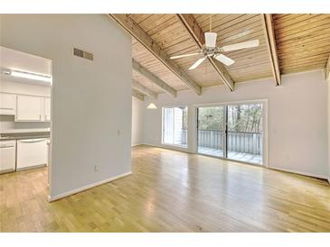 Bright living room with wood floors, exposed beams, and sliding doors to the balcony at 3817 Paces Ferry West, Atlanta, GA 30339