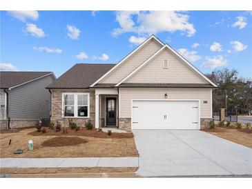 Charming home featuring stone accents, neutral siding, well-manicured lawn and two-car garage at 1723 Juniper Berry Way, Loganville, GA 30052