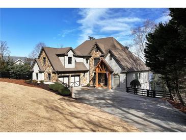 Beautiful exterior of a stone and siding home with an attached two-car garage, mature trees, and lush landscaping at 3330 Chimney Point Dr, Cumming, GA 30041