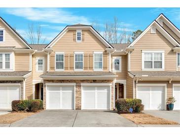 Charming townhome featuring a two-car garage and manicured landscaping at 1795 Waterside Nw Dr, Kennesaw, GA 30152