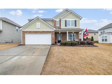 Charming two-story home with stone accents, attached garage and well-manicured lawn on a sunny day at 6371 Pierless Ave, Sugar Hill, GA 30518