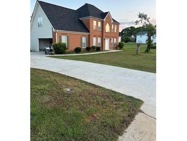 Traditional brick home with a well-maintained lawn and long concrete driveway at 3305 Wolverton Sw Ct, Conyers, GA 30094