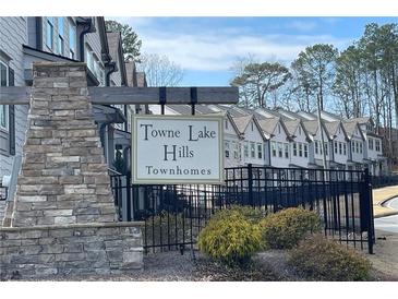 View of Towne Lake Hills townhome community with manicured landscaping and a decorative stone sign at 353 Vista Ln, Woodstock, GA 30189