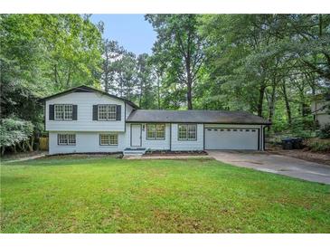 Charming two-story home with a well-manicured lawn, attached garage, and lush green trees in the background at 545 Birch Ln, Lawrenceville, GA 30044