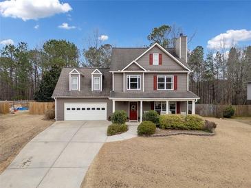 Charming two-story home with red shutters, a well-manicured lawn, and a driveway leading to an attached two-car garage at 128 Holly Pl, Canton, GA 30115